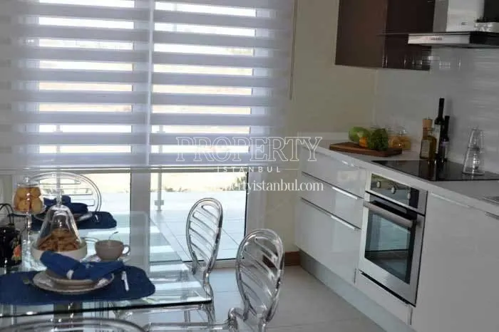 White kitchen with a glass dining table in Cornerlife Gunesli