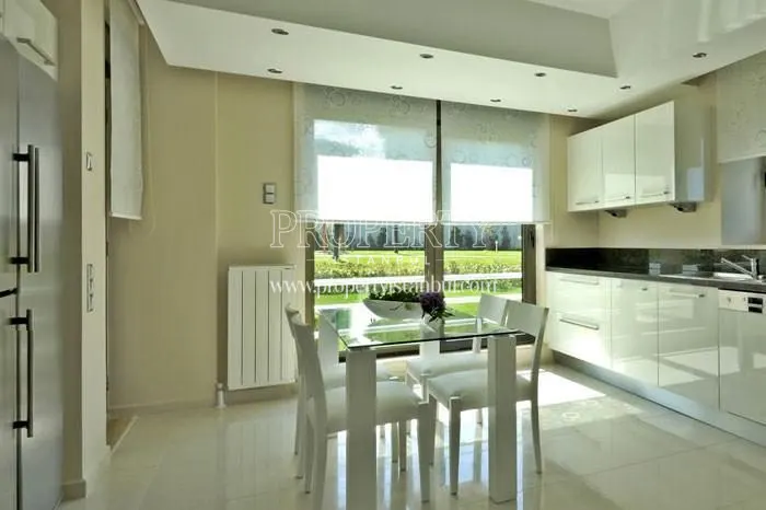 White kitchen with a glass dining table in Tepe Park Villalari