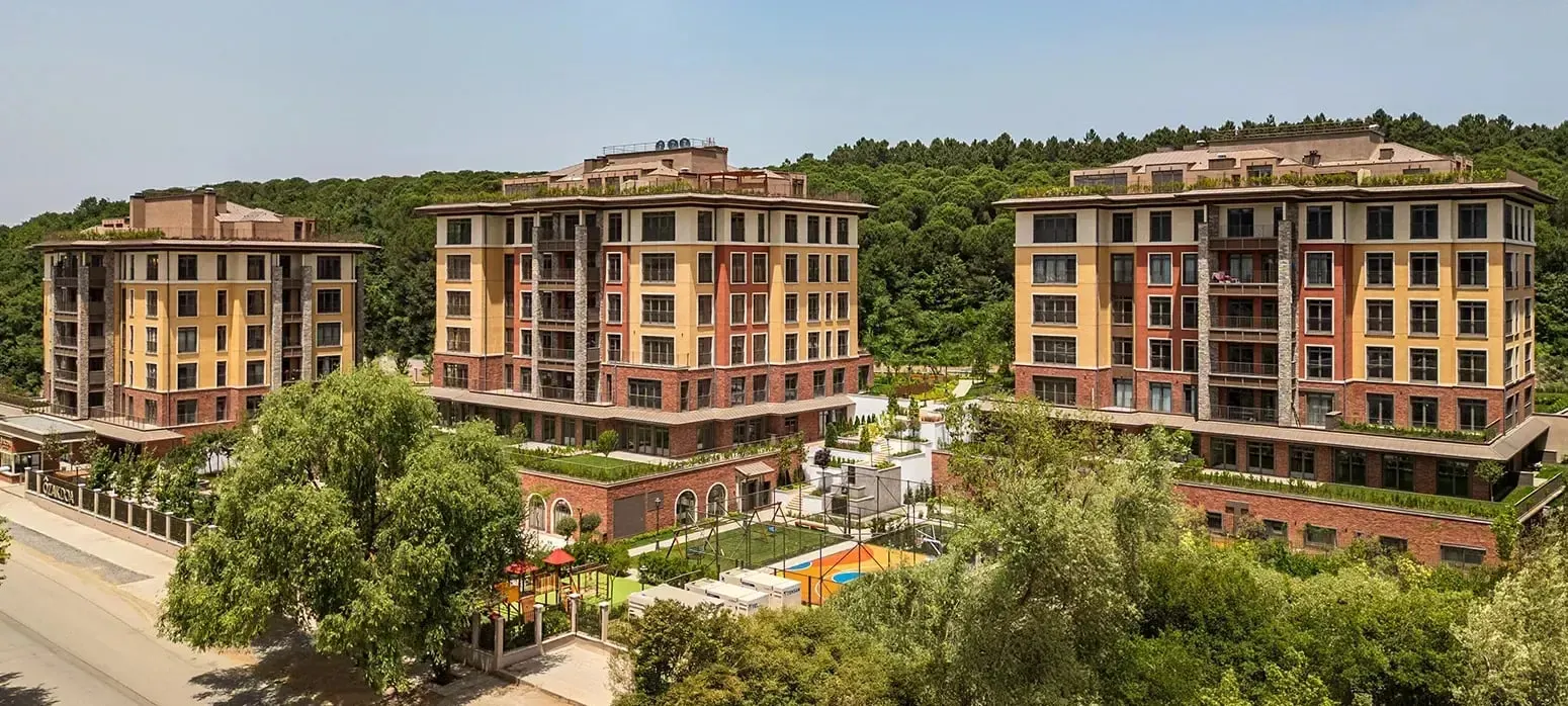 The three Ozak DOA Gokturk blocks seen from the street, with the forest behind